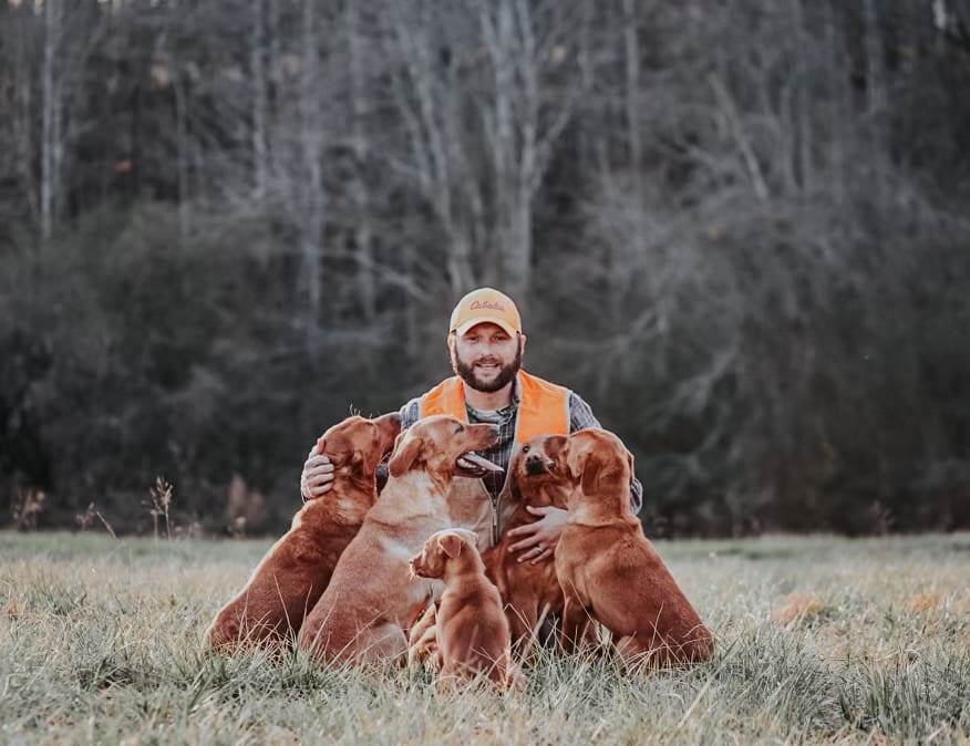 Man in hunting gear with four dogs.