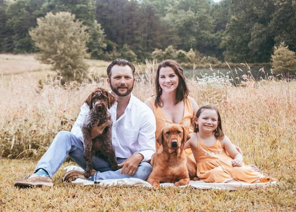 Family portrait with two dogs in field.